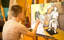 Young man painting picture — Stock Photo