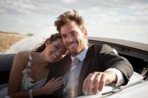 Newlywed couple riding in convertible — Stock Photo