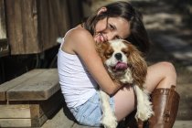 Портрет улыбающейся девушки, обнимающей собаку на ступеньках — стоковое фото