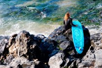 Женщина сидит с доской для серфинга — стоковое фото