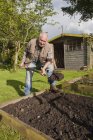 Старший мужчина, копает землю в саду — стоковое фото