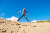 Дівчина-підліток стрибає на піску — стокове фото