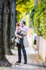 Отец носит дочь на тротуаре — стоковое фото