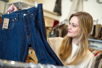 Молода жінка дивиться на пару джинсів — стокове фото