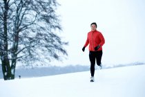 Женщина, бегущая в зимнем лесу — стоковое фото