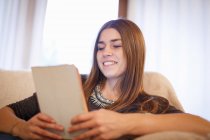 Mujer joven usando tableta digital en el sofá - foto de stock