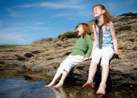 2 девочки ставят ноги в холодный каменный бассейн — стоковое фото