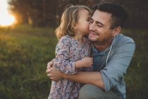 Menina beijando pai na bochecha no campo — Fotografia de Stock