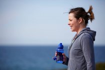 Young woman at coast taking exercise break — Stock Photo