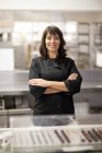 Portrait of woman in commercial kitchen with arms folded — Stock Photo