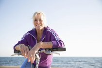Старшая женщина на велосипеде на пляже — стоковое фото