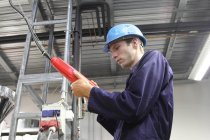 Eletricista masculino verificando cabo de alimentação na fábrica — Fotografia de Stock
