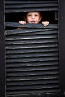 Menino de criança espreitando pela janela — Fotografia de Stock