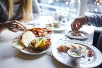 Schnappschuss von jungen Paaren beim Fingerfood-Essen im Café — Stockfoto