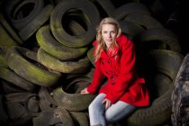 Дівчина-підліток сидить на викинутих шинах — стокове фото
