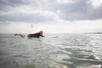 Mujer mayor en tabla de surf en el mar, paddleboarding - foto de stock