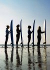 Quatro surfistas femininas em pé em uma praia — Fotografia de Stock