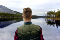 Вид сзади человека, смотрящего на красивое озеро — стоковое фото