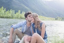 Молодой человек целует девушку на берегу реки Точе, Пьемонте, Италия — стоковое фото