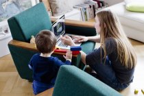 Mulher adulta média e bebê filho olhando para laptop na sala de estar — Fotografia de Stock