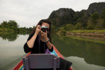 Femme prenant des photos en bateau sur la rivière Nam Song, Vang Vieng, Laos — Photo de stock