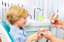 Boy in dentists chair learning how to brush teeth — Stock Photo