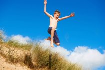 Niño feliz saltando en la playa - foto de stock