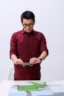 Young male designer photographing color samples with smartphone — Stock Photo