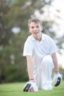 Rapaz ajoelhado no campo de críquete — Fotografia de Stock
