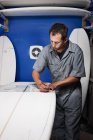 Средне взрослый мужчина измеряет доску для серфинга в мастерской — стоковое фото