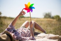Woman lying in on back holding windmill — Stock Photo