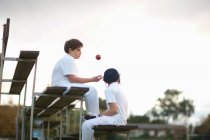 Rapazes em bancadas no campo de críquete — Fotografia de Stock