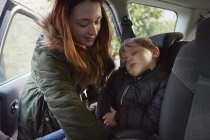 Mother removing sleeping toddler son from car backseat — Stock Photo