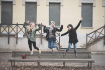 Three sisters jumping on park bench — Stock Photo