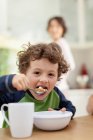 Хлопчик їсть сніданок на кухні, фокус на передньому плані — стокове фото