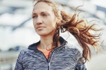 Portrait of female runner with flyaway hair on city footbridge — Stock Photo