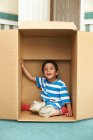 Niño jugando en caja de cartón - foto de stock