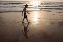 Niño caminando en olas en la playa - foto de stock