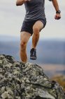 Man trail running on rocky cliff top, Keimiotunturi, Lapland, Finland — Stock Photo