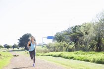 Femme adulte moyenne courir sur la piste de terre dans le parc — Photo de stock