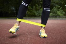 Gambe di una giovane donna che si allena nel parco, fascia elastica di resistenza — Foto stock