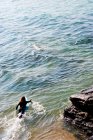 Vista posteriore della donna sdraiata sulla tavola da surf in acqua — Foto stock