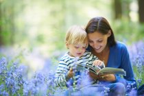 Madre e hijo leyendo en el bosque - foto de stock
