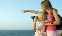 Young girl pointing finger while boy looking in binoculars — Stock Photo