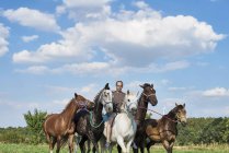 Homme adulte moyen chevauchant et menant six chevaux dans le champ — Photo de stock