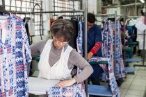 Працівник прасувальної сукні на швейній фабриці — стокове фото