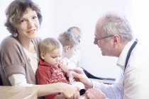 Child on mother's lap being examined by doctor — Stock Photo