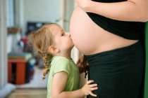 Menina beijando mãe grávida? s barriga — Fotografia de Stock