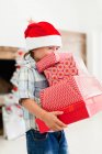 Junge mit Weihnachtsmütze und Weihnachtsgeschenken — Stockfoto