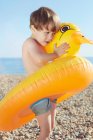 Junge umarmt entchenförmigen Schwimmer — Stockfoto